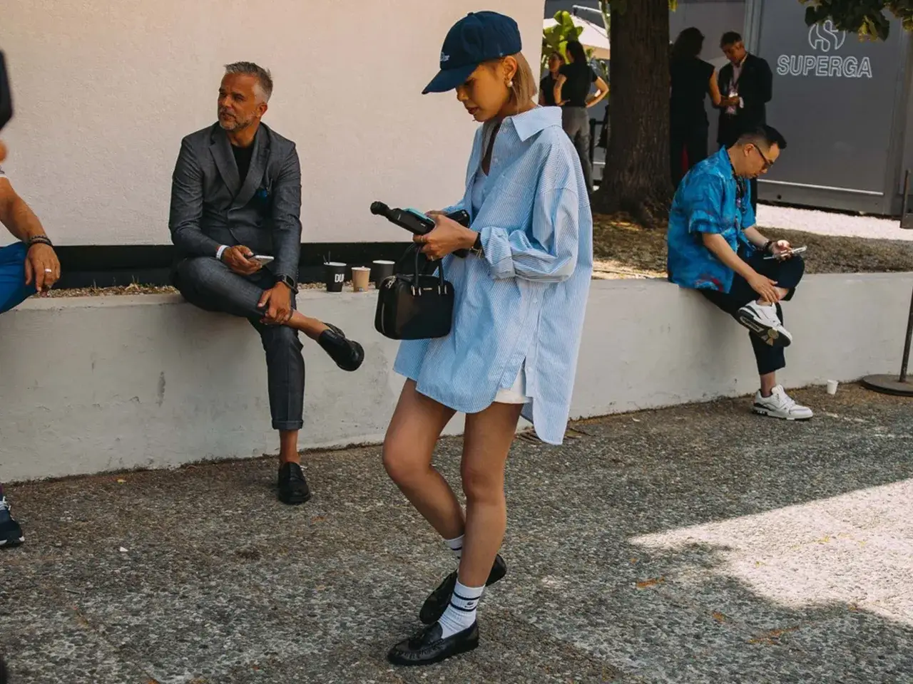 Kobieta w czapce i luźnej koszuli, na nogach ma czarne loafersy co to za buty, które świetnie komponują się z białymi skarpetkami.