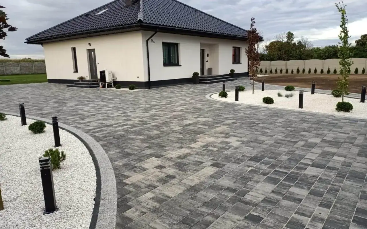 Nowoczesne aranżacje kostka brukowa wzory tworzą elegancki podjazd i ścieżki wokół białego domu.