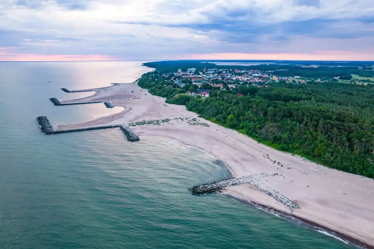 Widok z lotniska na wybrzeże z kamiennymi falochronami i lasem. Miasto nad morzem, gdzie można podziwiać piękne lotniska nad morzem.