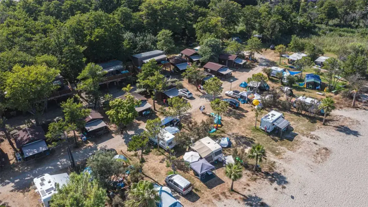 Vue aérienne d'un camping en Corse, avec des mobil-homes, tentes et camping-cars. Une scène paisible, loin de toute agression.