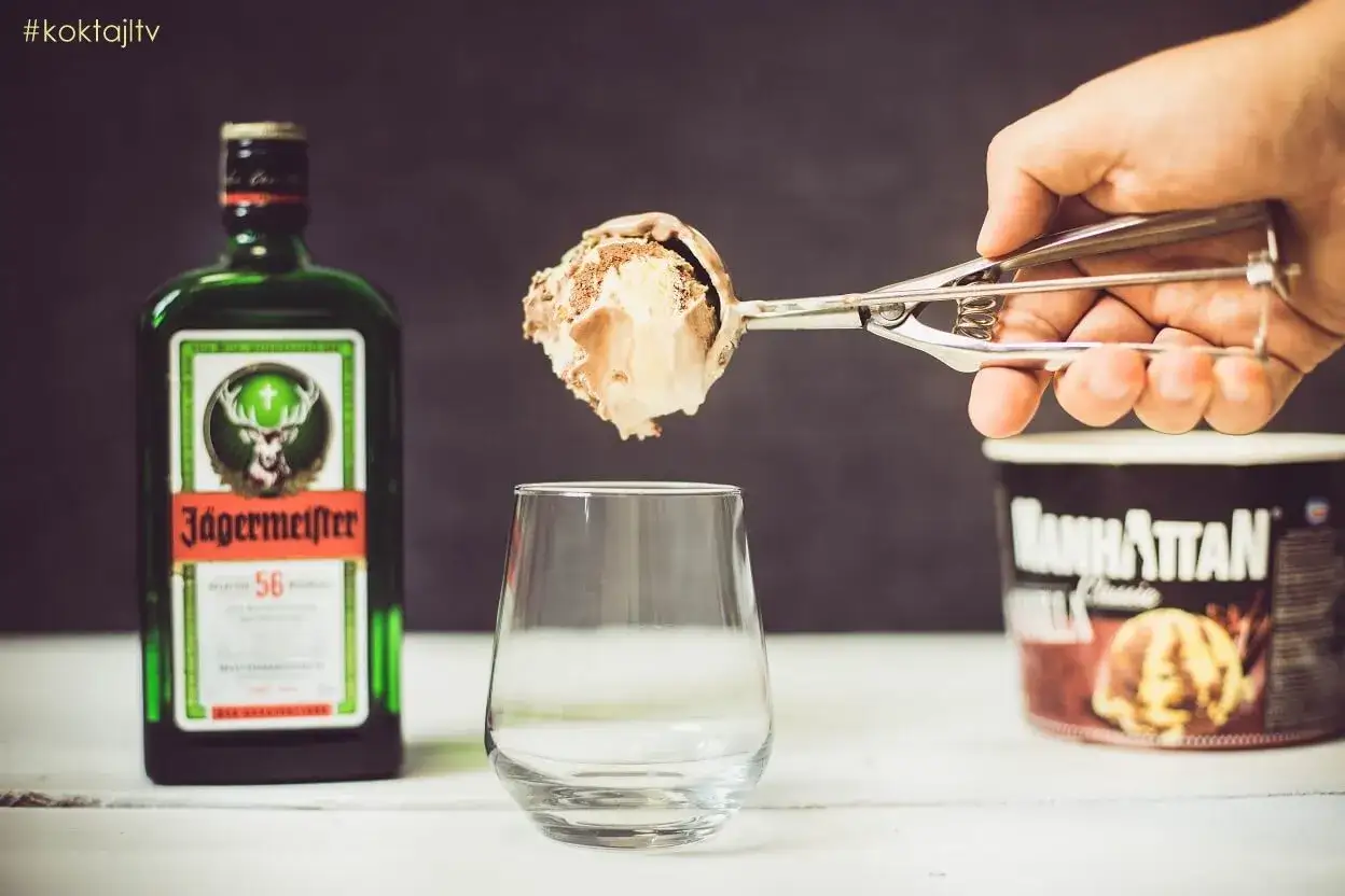Łyżka z lodami zbliża się do szklanki, obok butelka Jägermeistera. Czas na deser z nutą alkoholu, może nawet jagermeister na ciepło?