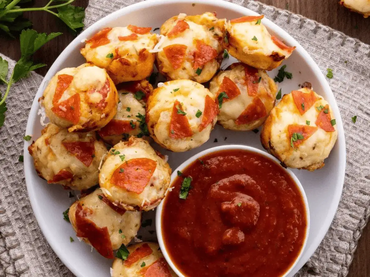 Kleine, runde Pizza-Bites aus Pizzateig mit K&auml;se und Pepperoni, serviert mit Tomatensauce. Perfekt als Fingerfood.