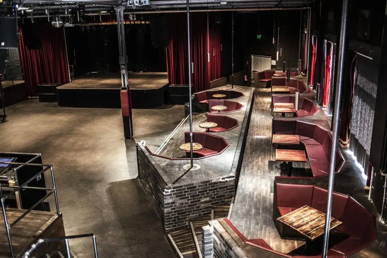 Leerer Festsaal Kreuzberg mit B&uuml;hne, roten Samtvorh&auml;ngen und vielen roten Sitznischen mit Tischen.