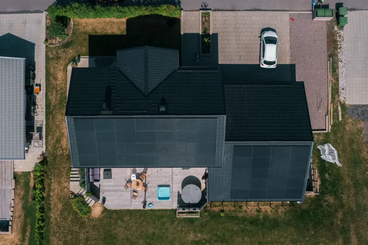 Soldags i Sverige AB: Ett modernt hus med solpaneler, altan, bubbelpool och en vit bil p&aring; uppfarten.