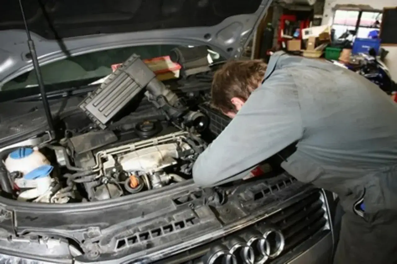 Samochód z otwartą maską, mechanik patrzy na silnik