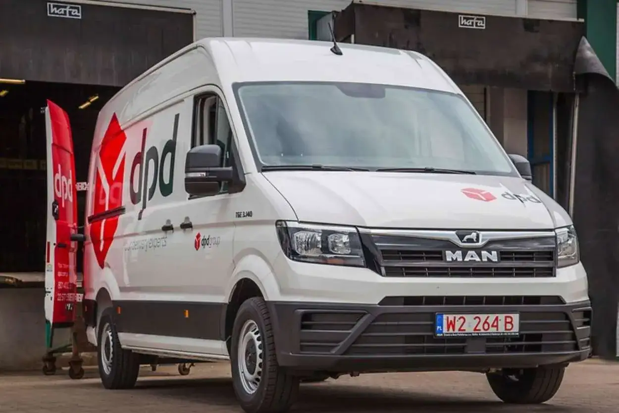 Ein wei&szlig;er Kleinbus von DPD steht vor einem Lager. Er transportiert Pakete von Polen nach Deutschland.