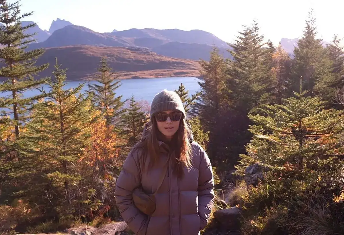 Lily Collins njuter av den svenska naturen med en sjö och berg i bakgrunden.