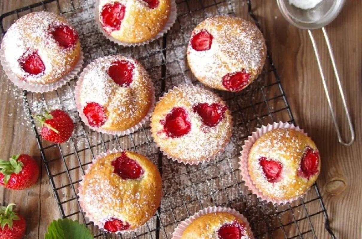Pyszne muffinki z truskawkami, posypane cukrem pudrem. Idealne na każdą okazję, bo to uniwersalny przepis na muffinki.