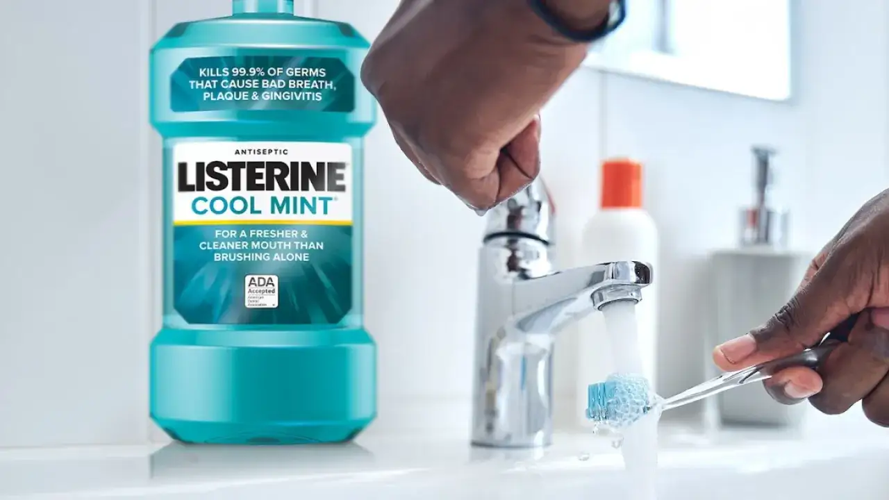 Płyn do płukania jamy ustnej Listerine Cool Mint. Czy używać go przed czy po myciu zębów? Woda leje się na szczoteczkę.