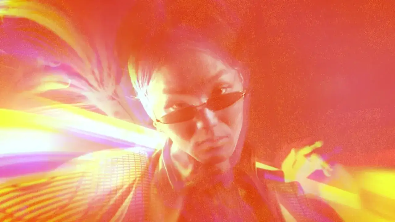 A woman with sunglasses stares ahead, surrounded by vibrant, abstract light streaks and patterns, reminiscent of After Effects overlays.