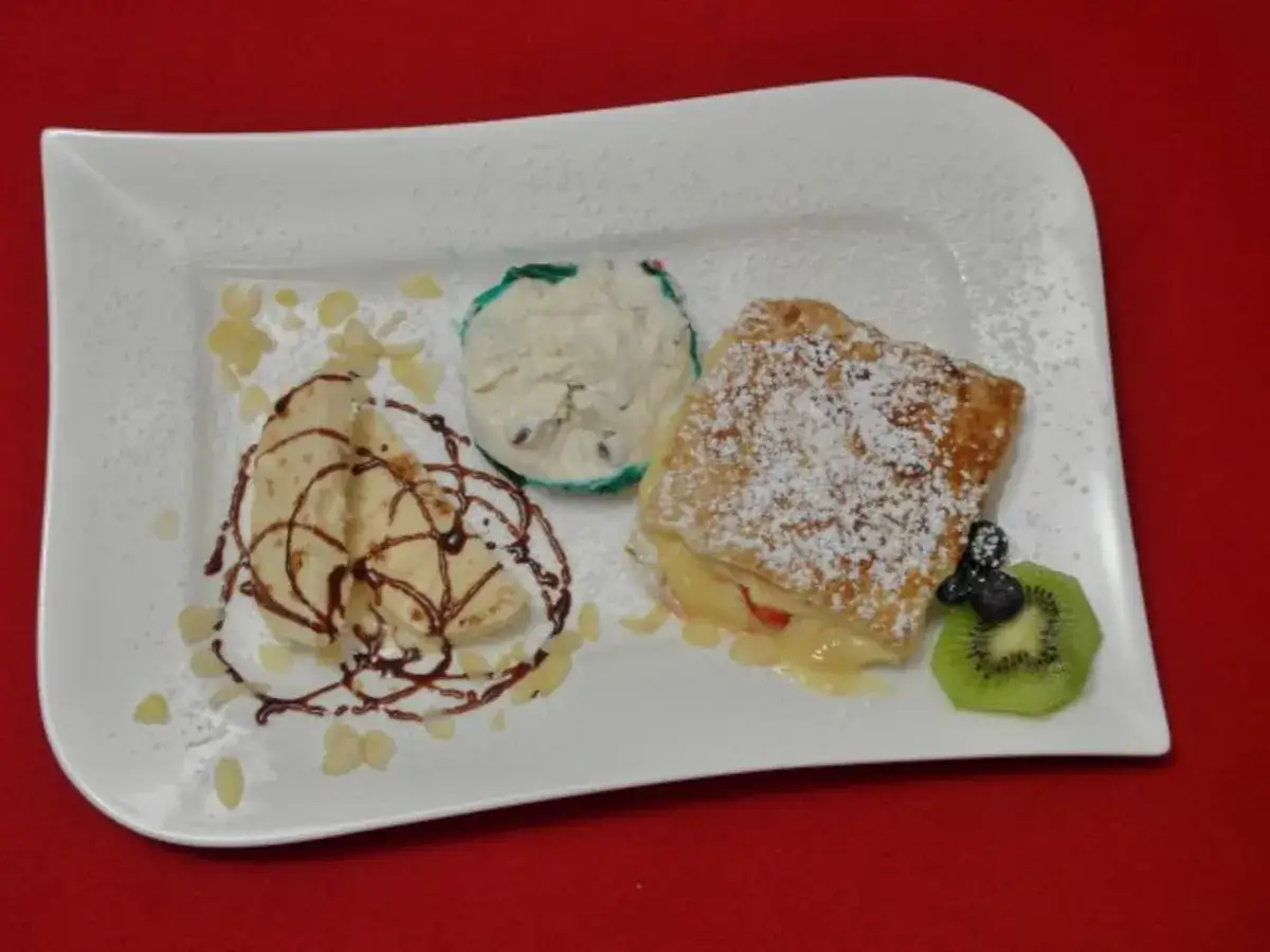K&ouml;stliche italienische Nachspeisen: ein knuspriges Geb&auml;ck mit Fruchtf&uuml;llung, Eis und Crepes mit Schokoladensauce, garniert mit Kiwi und Mandelsplittern.
