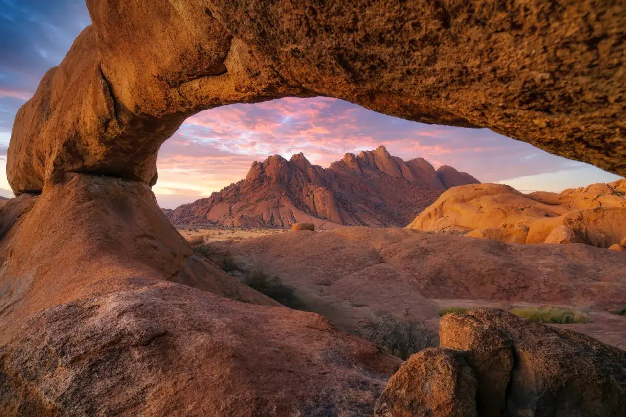 Skalny łuk na tle spektakularnego zachodu słońca nad Spitzkoppe w Namibii.