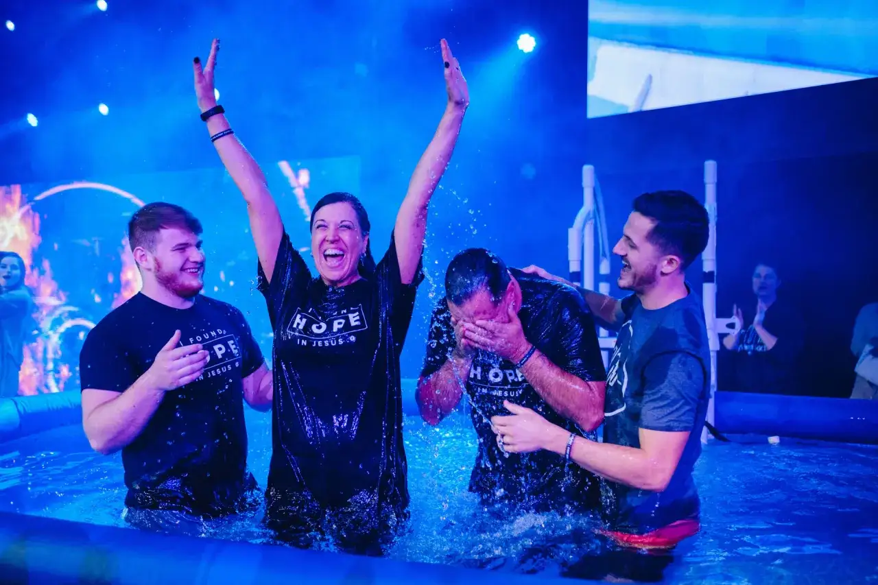 Joyful baptism in blue water. People are being immersed, questioning if do you have to be baptized to be saved.