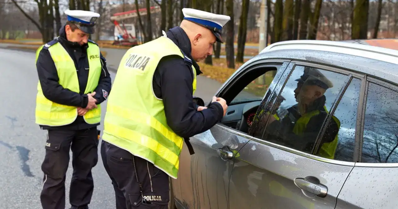 Policjanci w kamizelkach odblaskowych kontrolują kierowcę. Nowy przepis dla kierowców może oznaczać mandat.