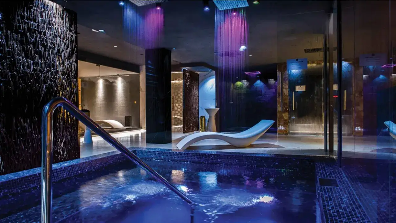 Nowoczesne spa nad morzem z basenem, kolorowe prysznice i leżaki.