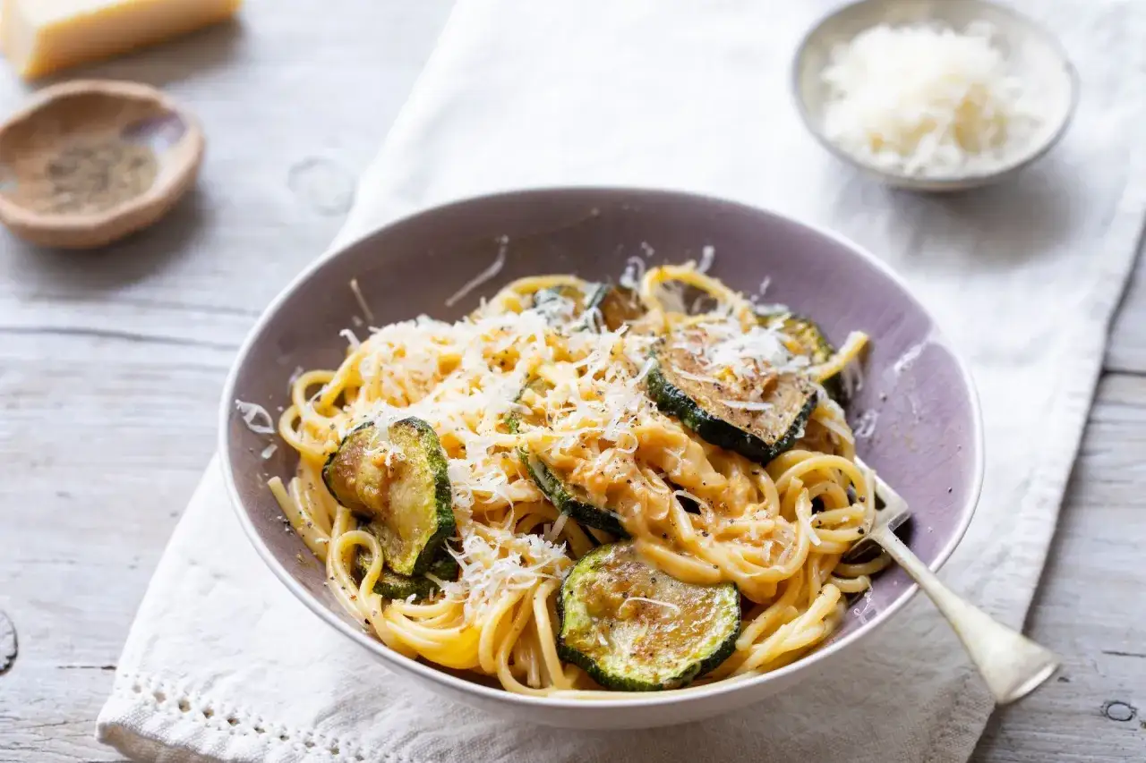 Pyszny makaron z cukinią i pieczarkami, posypany parmezanem. Idealny lekki obiad.