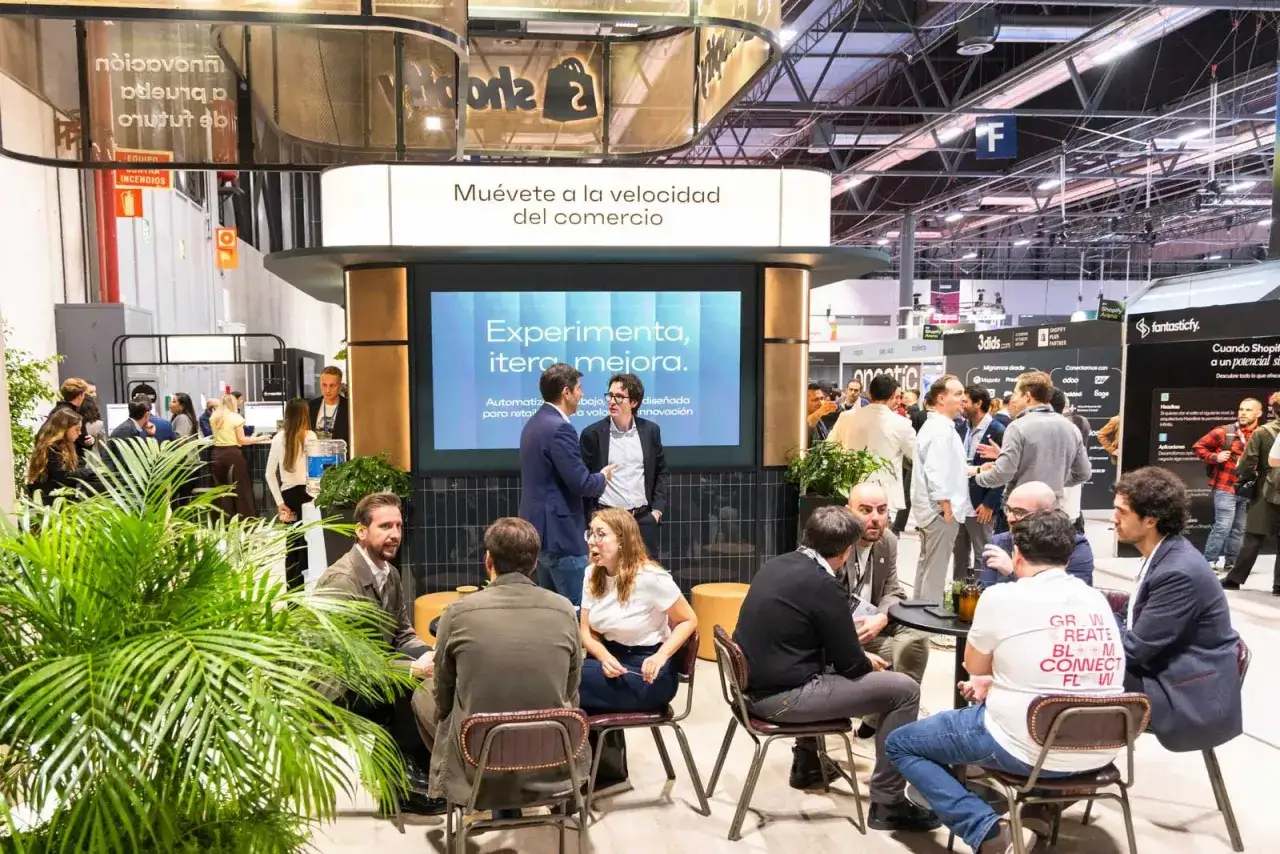 Gente conversando en una feria de emprendimiento, con una pantalla que dice 