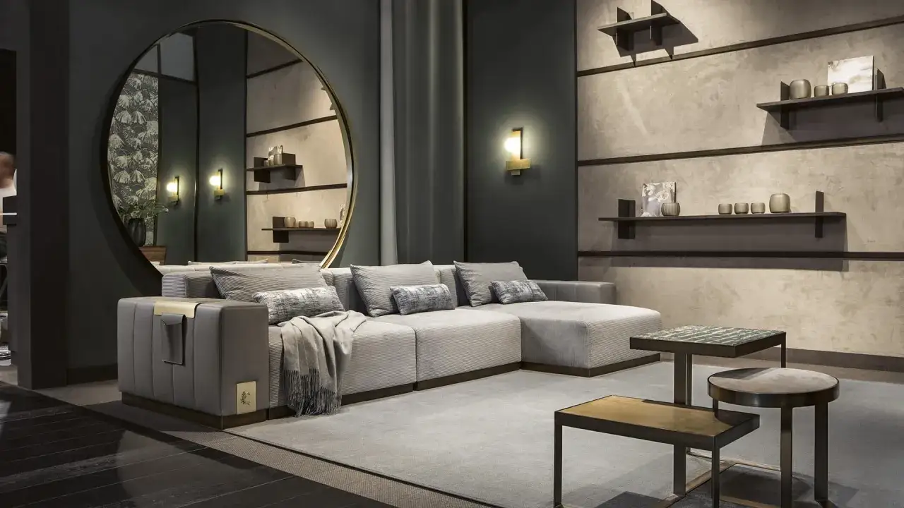 Idee per come arredare parete dietro divano: specchio rotondo, mensole con vasi e un divano modulare grigio.