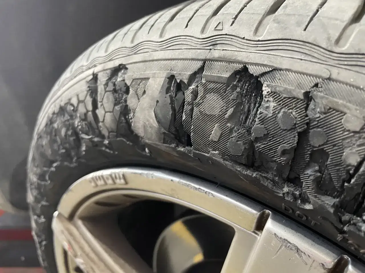 Neumático de coche con daños severos en el flanco. Si te pasa esto, esto es qué hacer si me pinchan las ruedas del coche: cambia la rueda.