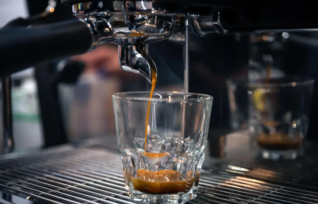 Gorący strumień ristretto kawy spływa do szklanki, tworząc gęstą cremę.