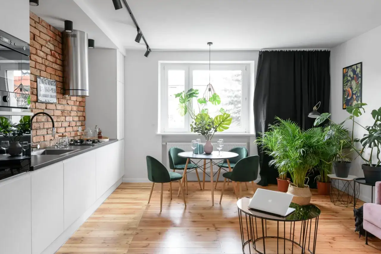 Nowoczesna kuchnia z jadalnią, gdzie **siatka bagua feng shui** inspiruje harmonię. Ceglana ściana, zielone krzesła i dużo roślin.