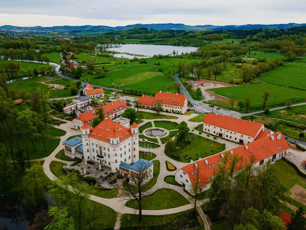 Pałac Wojan&oacute;w, z jego bogatą historią, otoczony zielenią i jeziorem, prezentuje się majestatycznie z lotu ptaka.