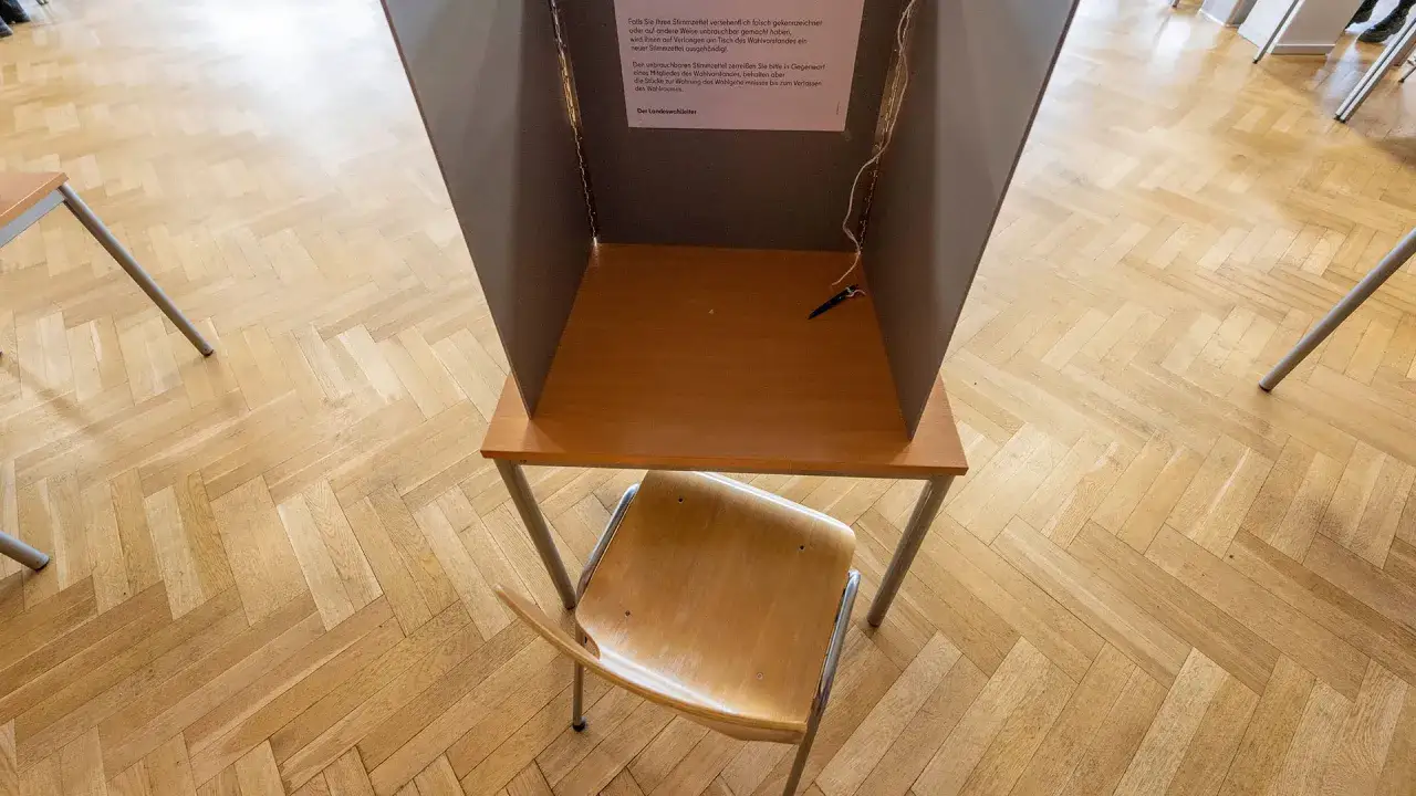 Eine Wahlkabine mit einem Stuhl davor. Ein Stift liegt auf dem Tisch. Die Wahl ist eine wichtige Entscheidung.