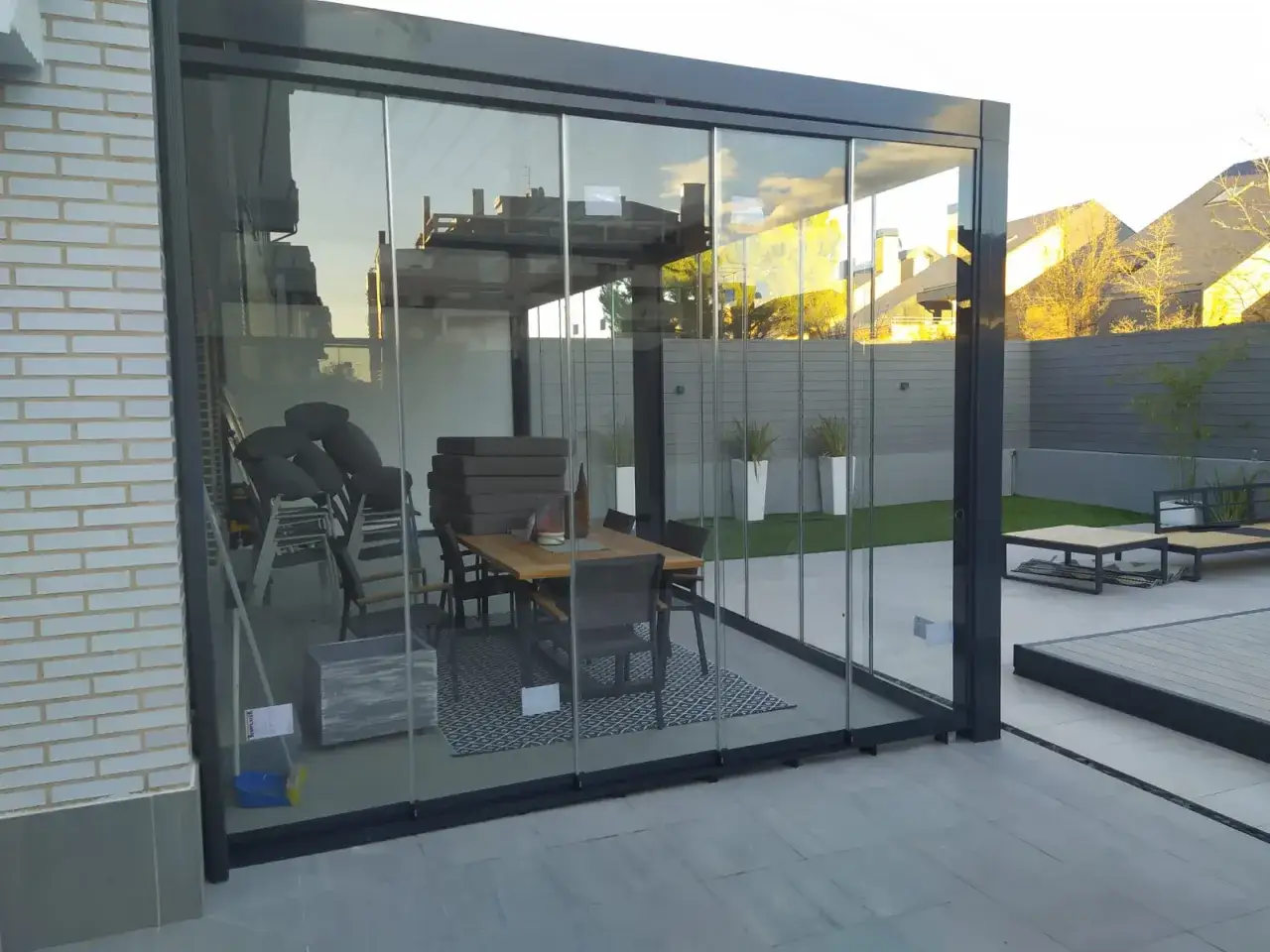 Terraza acristalada con mesa y sillas. Solución para como tapar la vista del vecino en terraza, creando un espacio privado y acogedor.