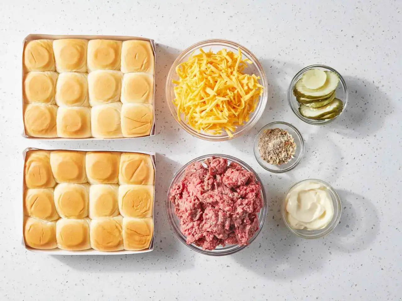 F&ouml;rberedelser f&ouml;r ett enkelt hamburgare recept: sm&aring; br&ouml;d, k&ouml;ttf&auml;rs, ost, pickles, kryddor och majonn&auml;s.