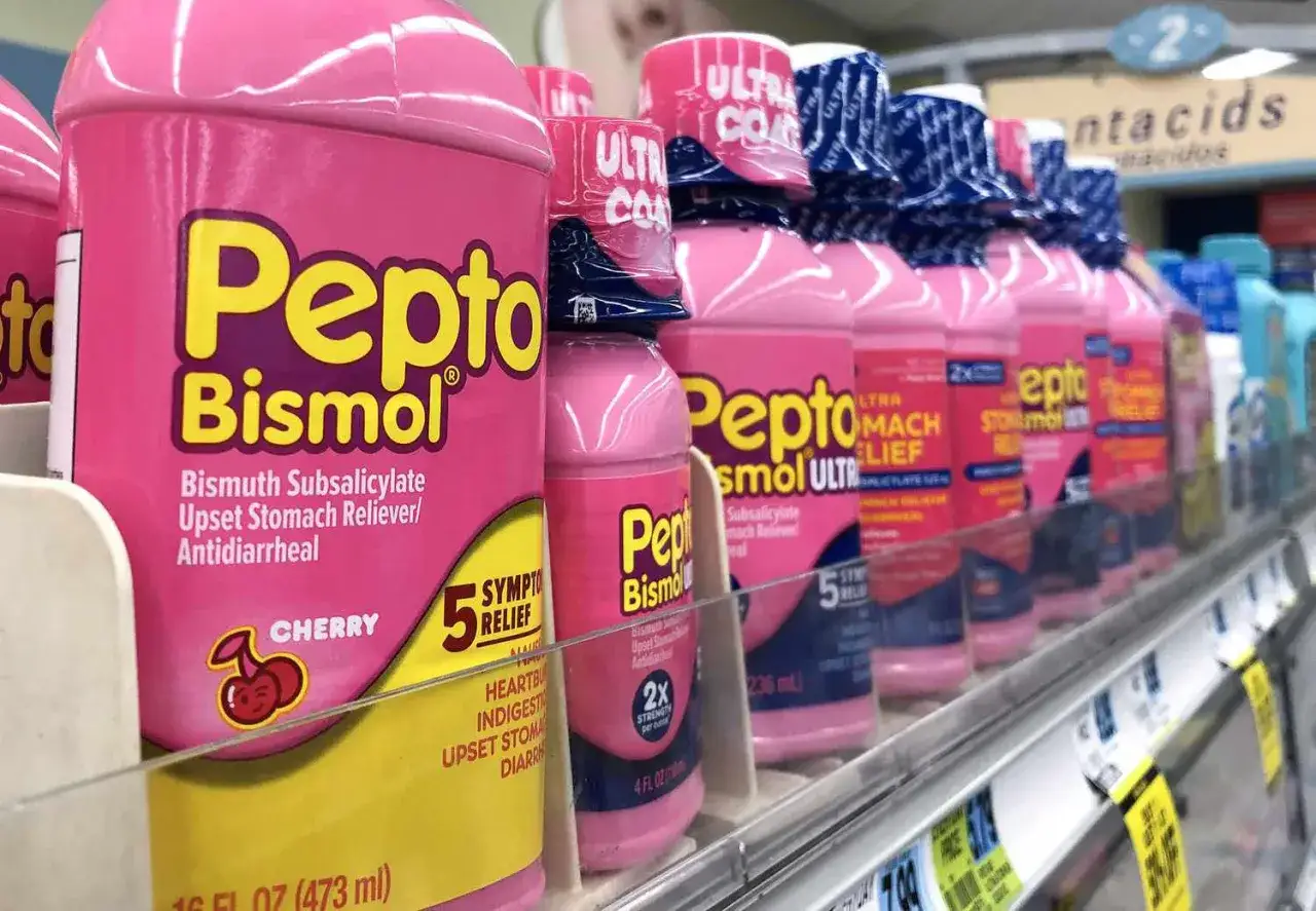 Rader av rosa flaskor med Pepto-Bismol, ett effektivt medicin mot diarré och oroliga magar, står uppradade på en hylla i en butik.
