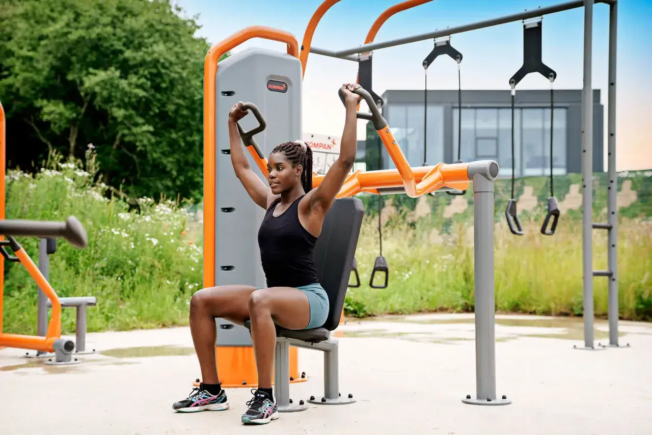 Frau trainiert an einem Ger&auml;t im Freien. Dies ist eine Form von Calisthenics, bei der das eigene K&ouml;rpergewicht genutzt wird.