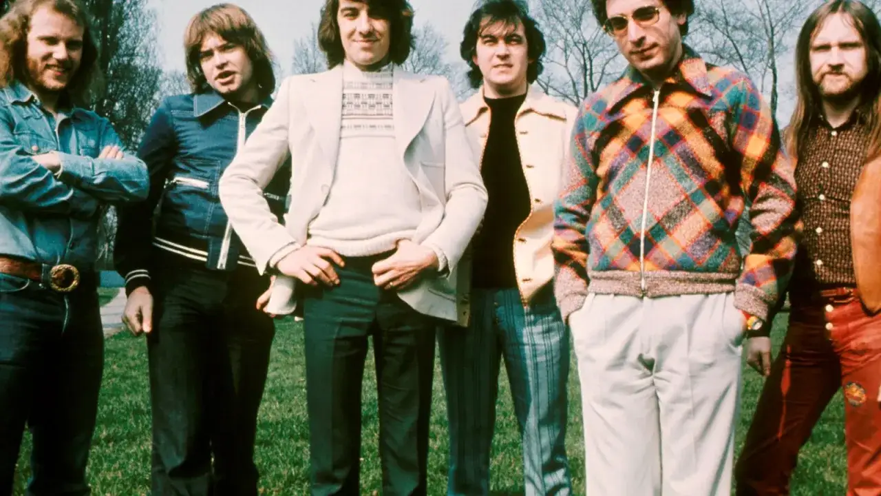 Zespół Procol Harum w stylowych strojach z lat 70. pozuje na tle drzew.