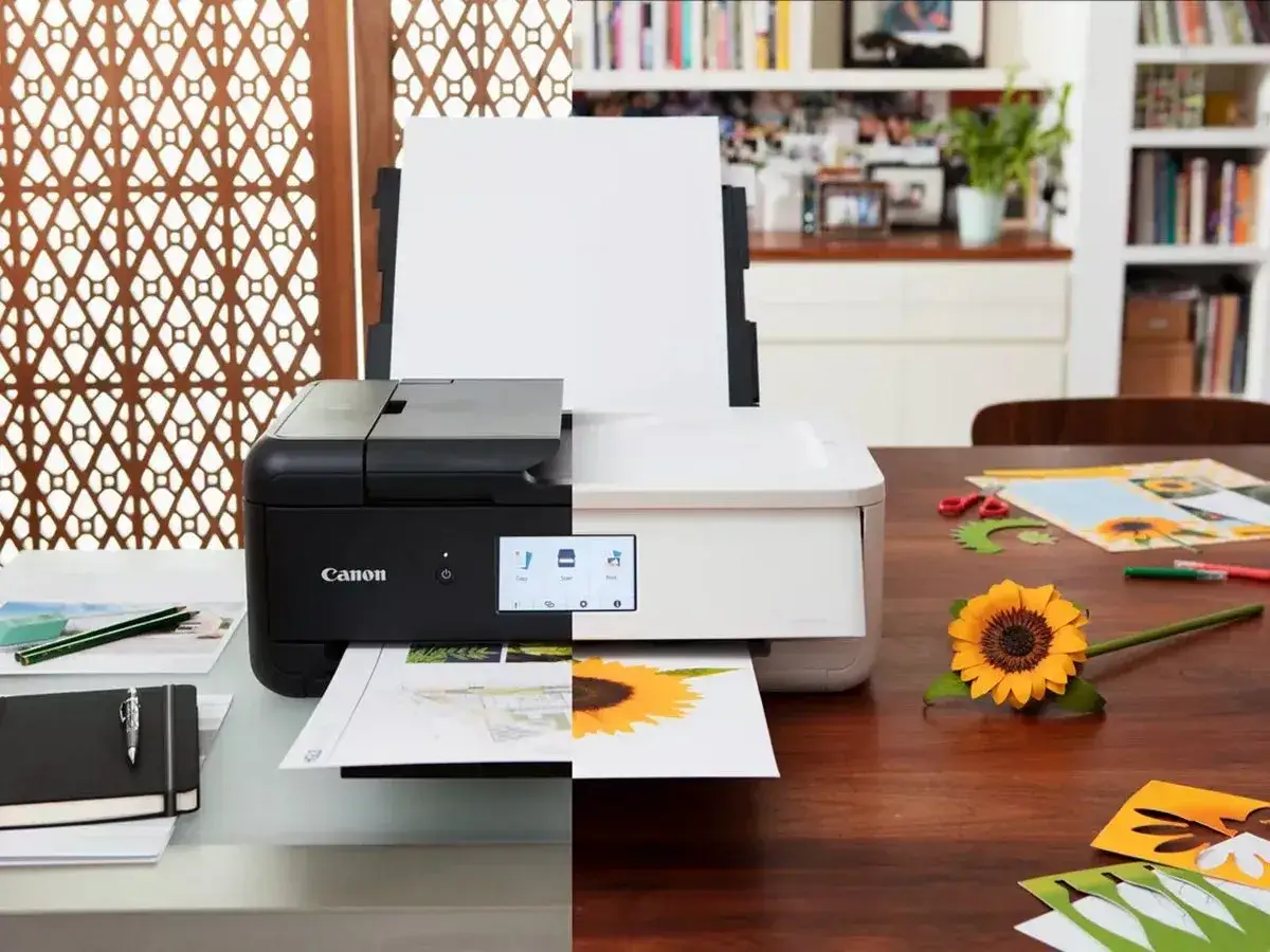 Stampante Canon che stampa foto su carta fotografica. Un girasole di carta e forbici suggeriscono un progetto creativo.