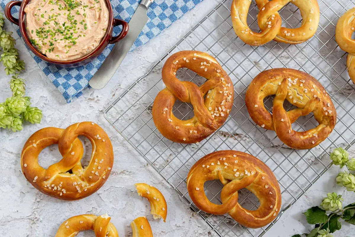 Frisch gebackene Brezeln mit grobem Salz, perfekt für ein pretzel bites rezept. Dazu eine Schale Dip und Hopfen.