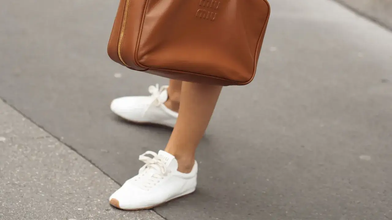 Bolso de cuero marrón y zapatillas blancas, un ejemplo de lujo silencioso.