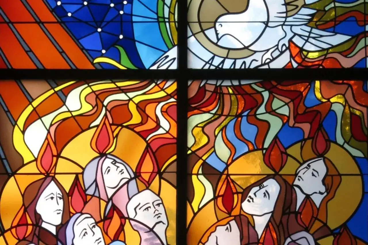 Stained glass depicts flames of the Holy Spirit descending on people, symbolizing Pentecost. This imagery helps us remember when is Pentecost Sunday this year.