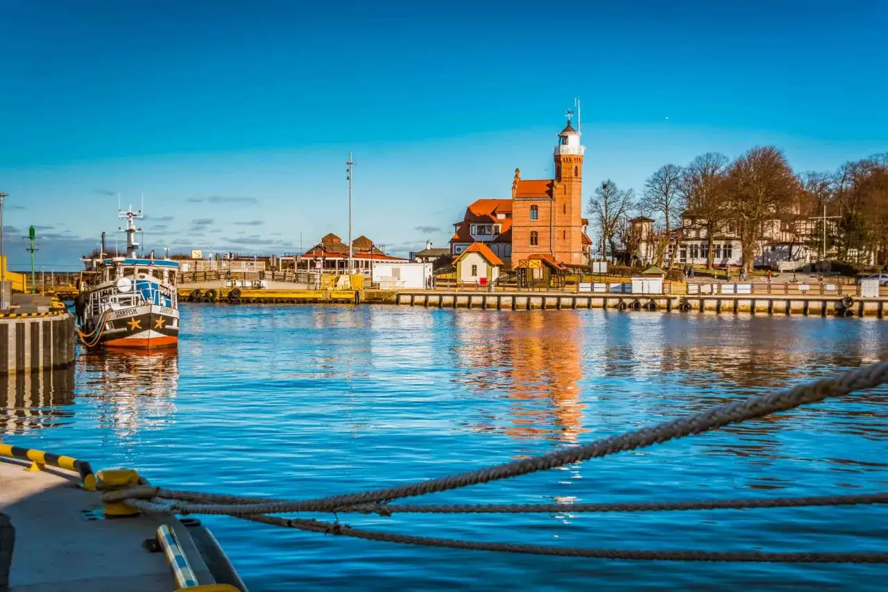 Port w Ustce z charakterystyczną latarnią morską i statkiem