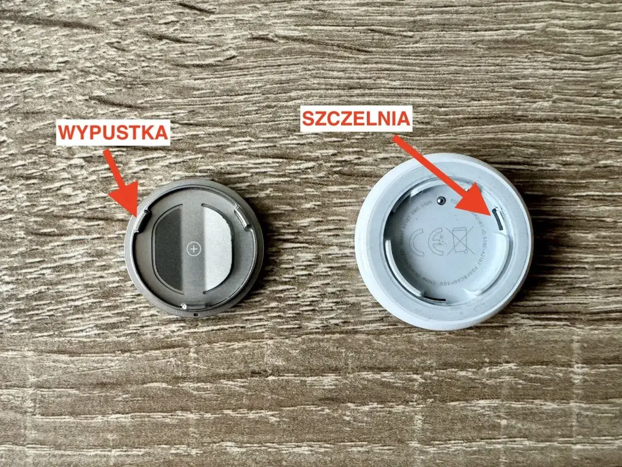Dwa AirTagi: jeden z wypustką do otwarcia, drugi z widoczną szczeliną. Czy airtag się ładuje? Nie, wymienia się baterię.