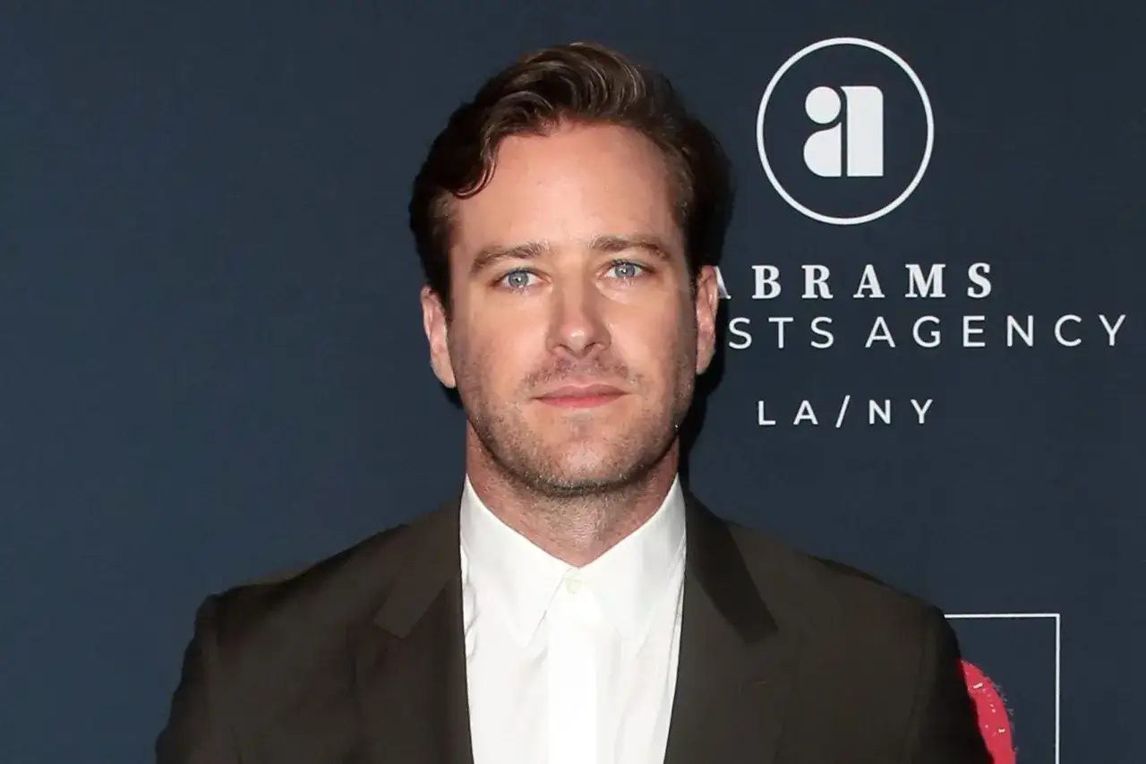 Armie Hammer, med bl&aring; &ouml;gon och m&ouml;rkt h&aring;r, b&auml;r en m&ouml;rk kavaj och vit skjorta. Bakgrunden visar en logotyp f&ouml;r Abrams Artists Agency.