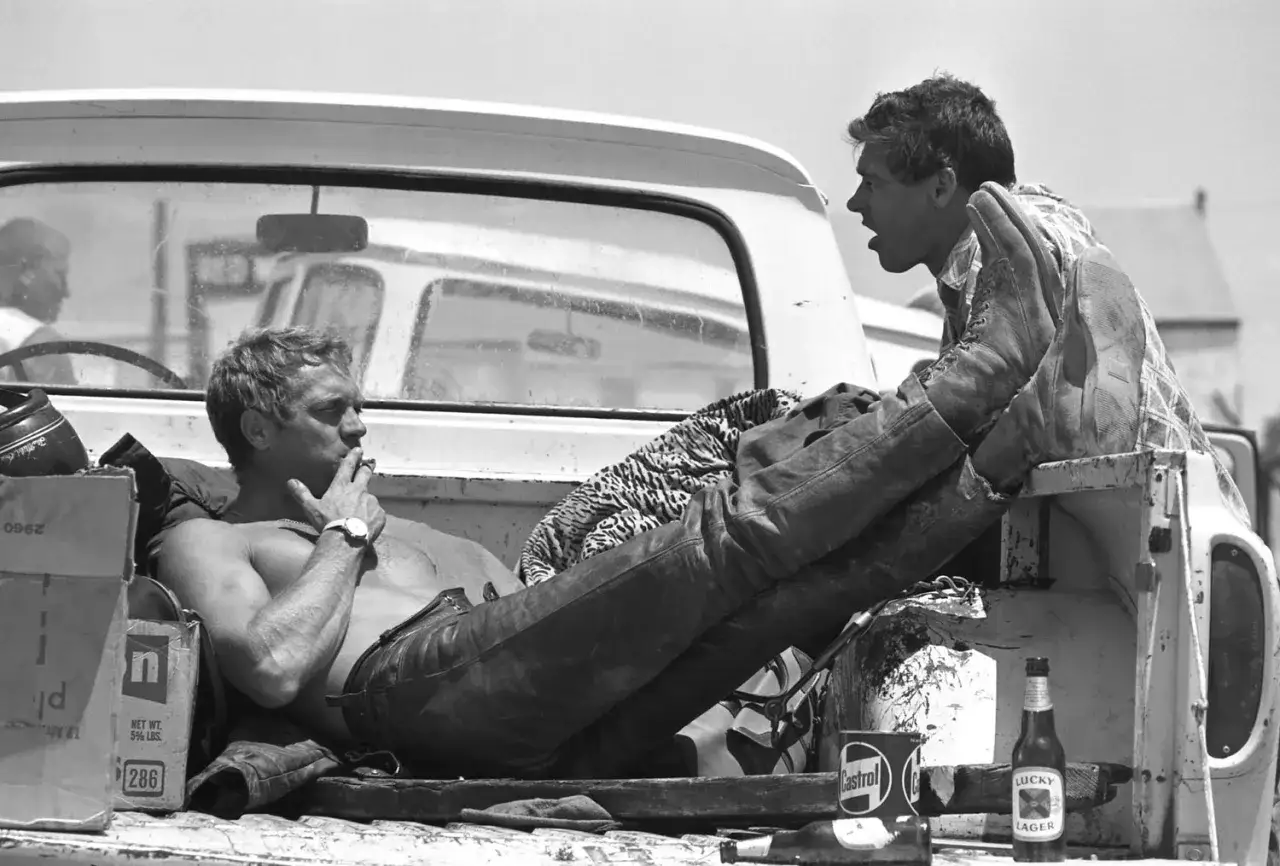 Steve McQueen, gwiazda swoich film&oacute;w, odpoczywa w pace pickupa, paląc papierosa. Obok butelka piwa Lucky Lager.
