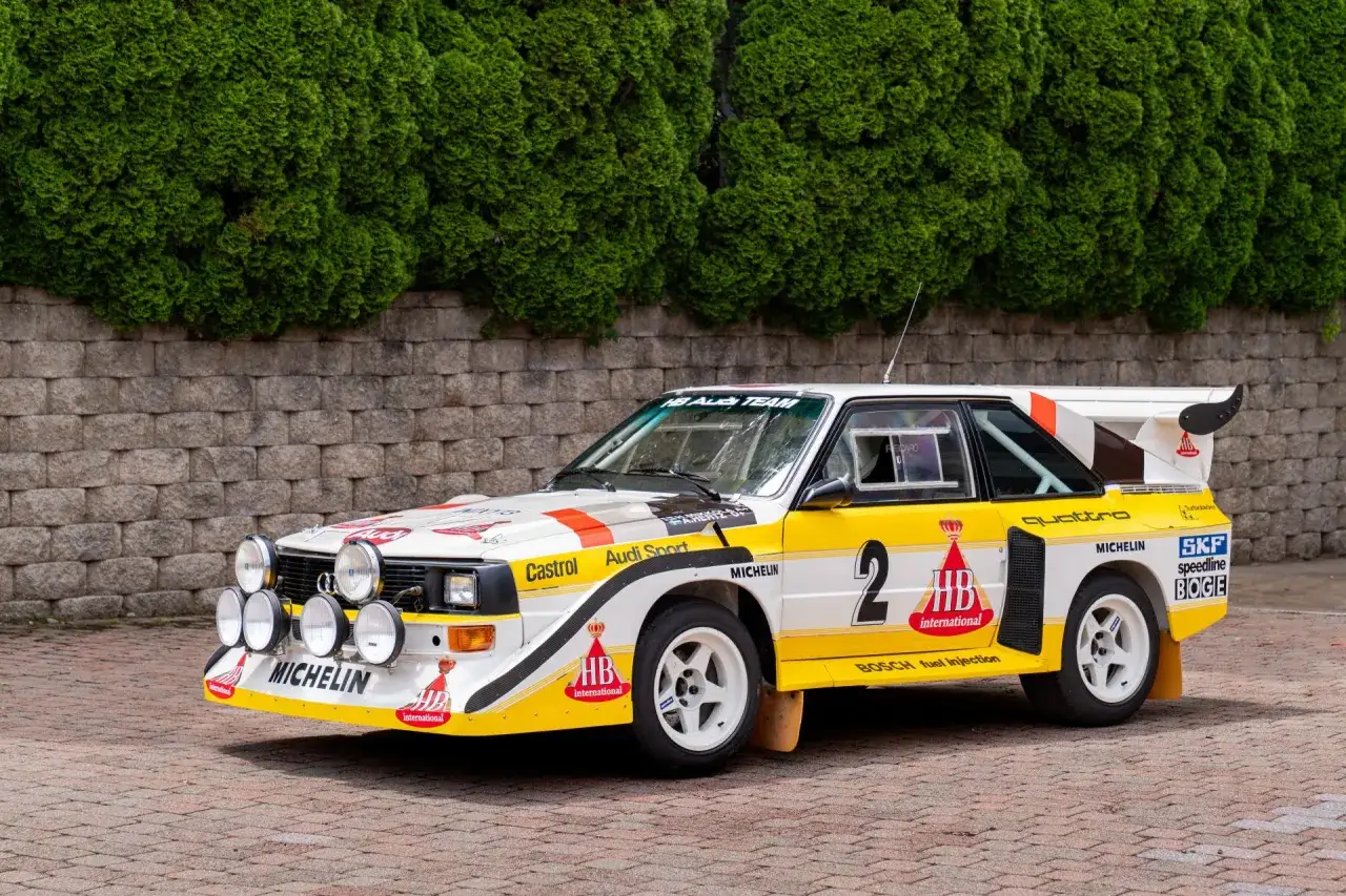 Ikoniczny Audi quattro S1 z numerem 2, gotowy do rajdu, z licznymi sponsorami na karoserii.