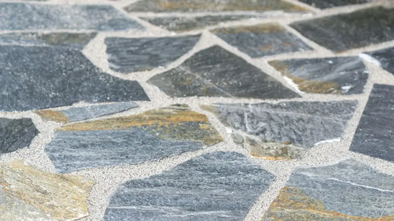 Detailaufnahme von polygonalplatten verlegen. Graue und gelbliche Steine mit hellem Fugenmörtel.