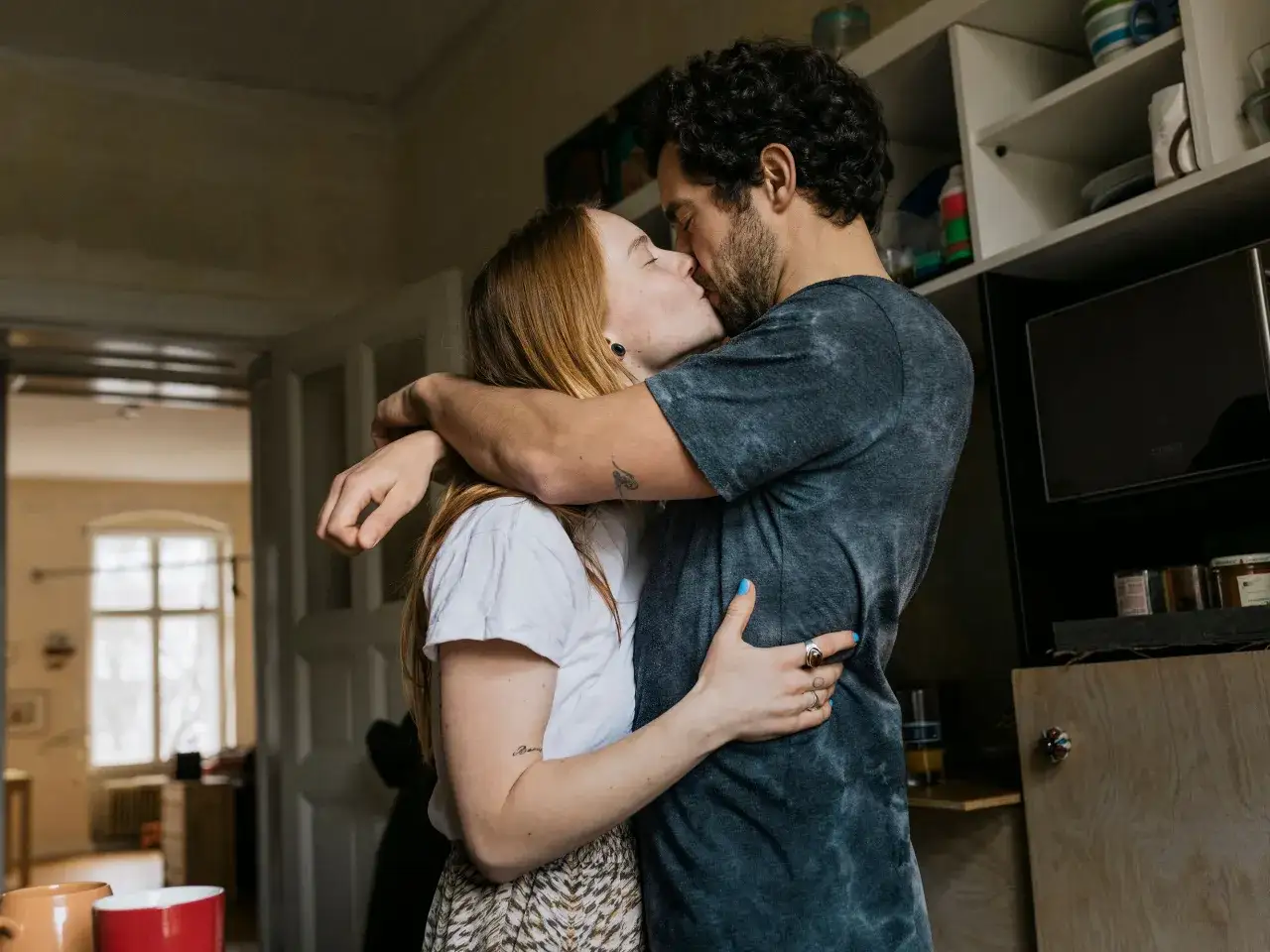 Pareja bes&aacute;ndose apasionadamente, ella con cabello pelirrojo y &eacute;l con barba. A pesar de la cercan&iacute;a, hay una sutil tensi&oacute;n, quiz&aacute;s un reflejo del apego evitativo.
