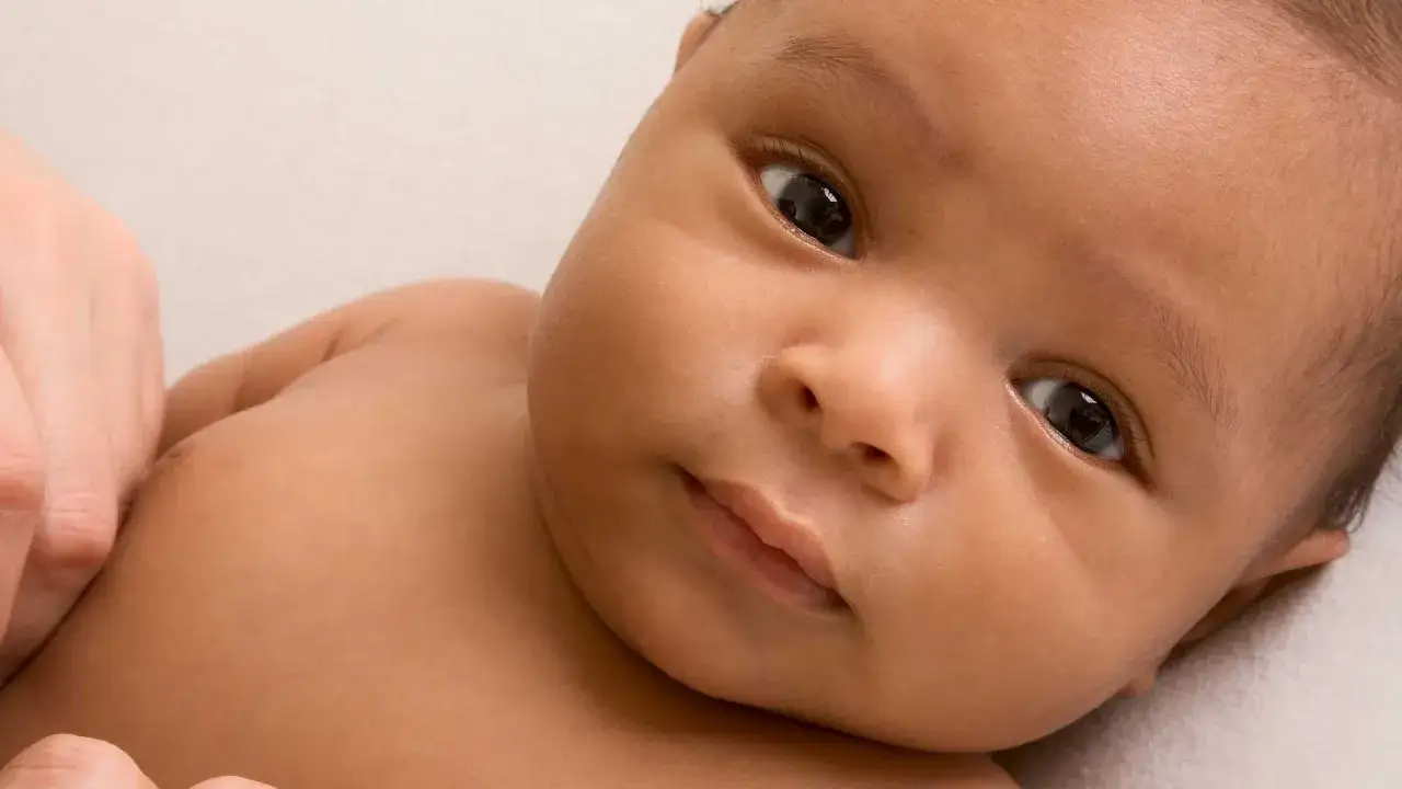 Ein neugeborenes Baby mit dunkler Haut und großen, dunklen Augen. Vielleicht ein Name wie Omar oder Layla, typisch für syrische Namen.