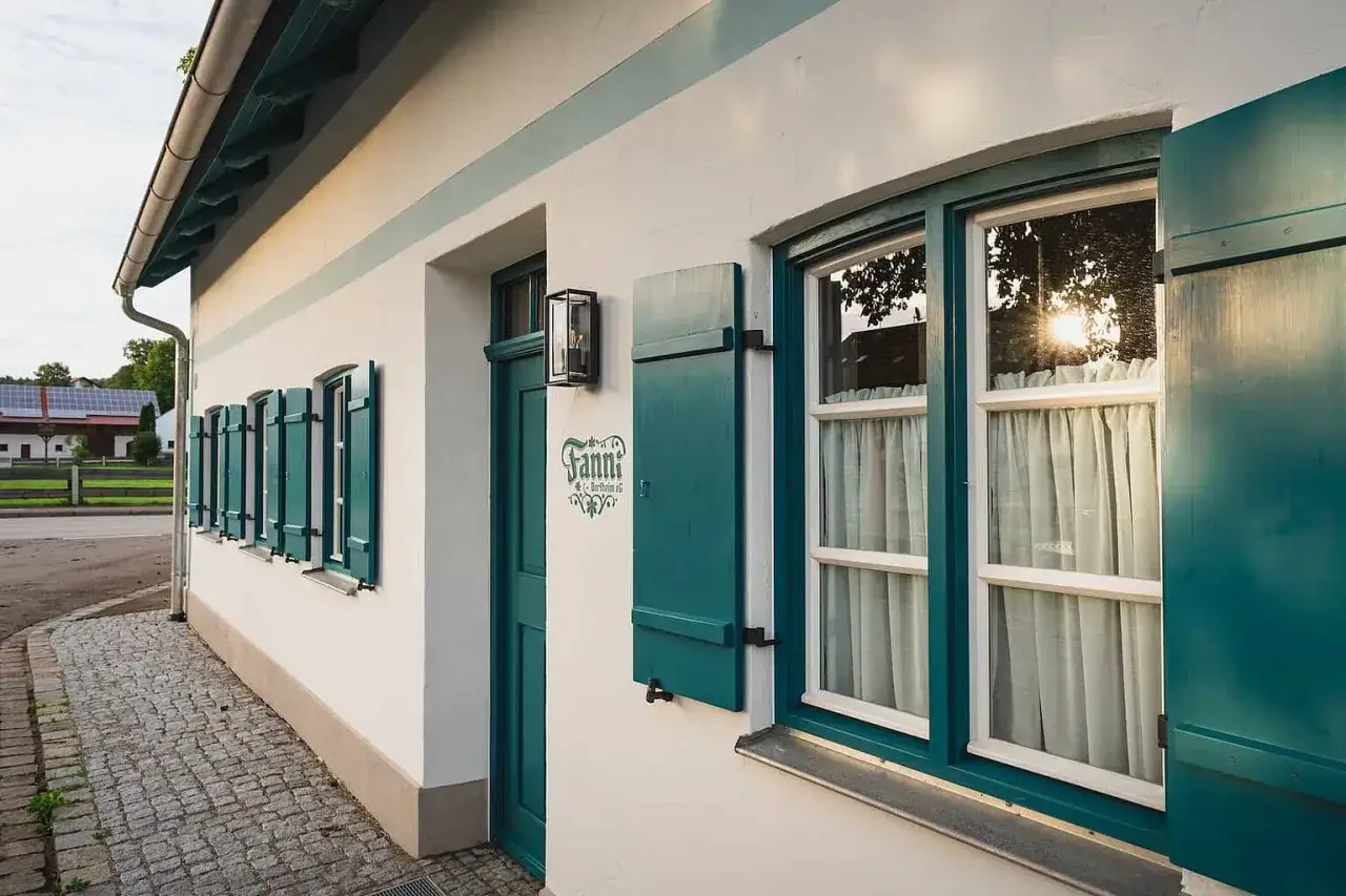 Ein Haus mit grünen Fensterläden und einem Schild