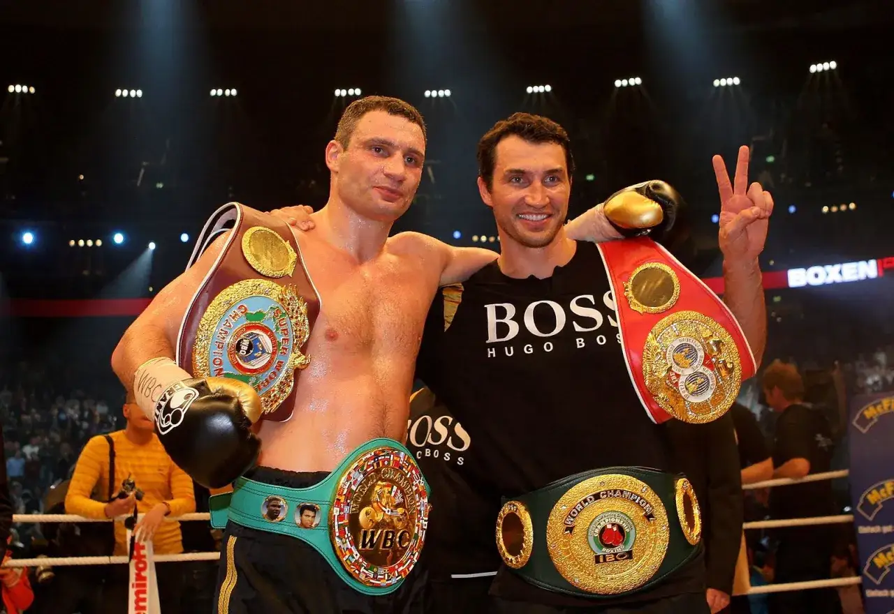 Vitali Klitschko and his brother celebrate their boxing victories, adorned with championship belts.