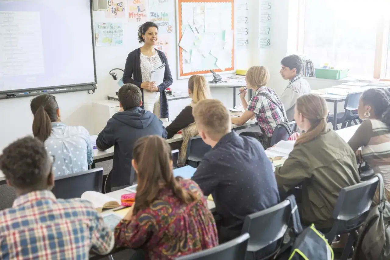 Lehrerin erkl&auml;rt Vokabeln auf Englisch. Sch&uuml;ler lernen und verbessern ihr Englisch im Unterricht.