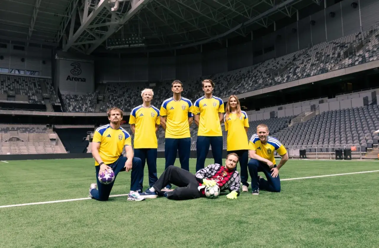 Julia Glenmark och hennes lagkamrater i svenska fotbollströjor poserar på en tom arena.