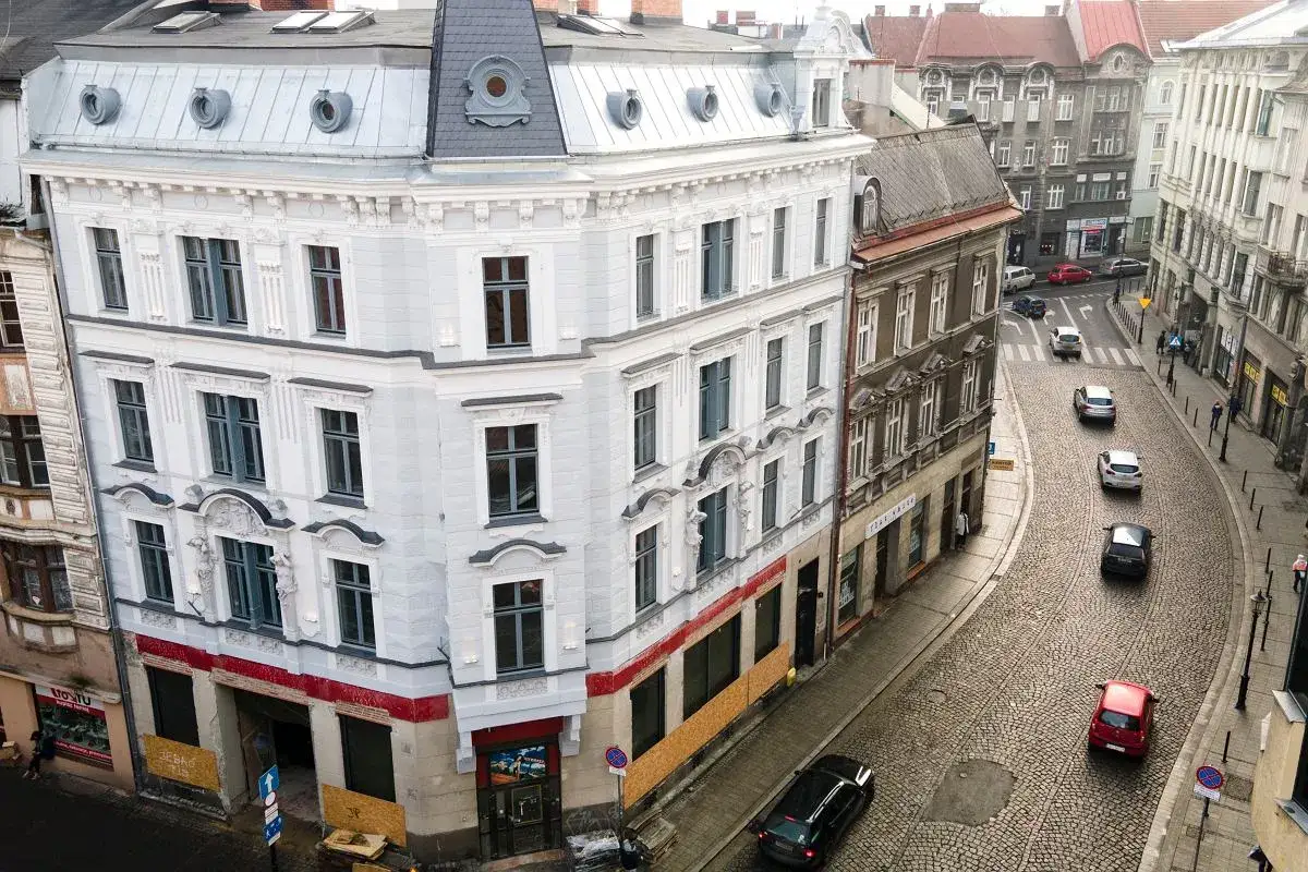 Ulica w polskim mieście, przypominająca architekturą Wiedeń. Kamienice, brukowana droga i samochody tworzą malowniczy widok.