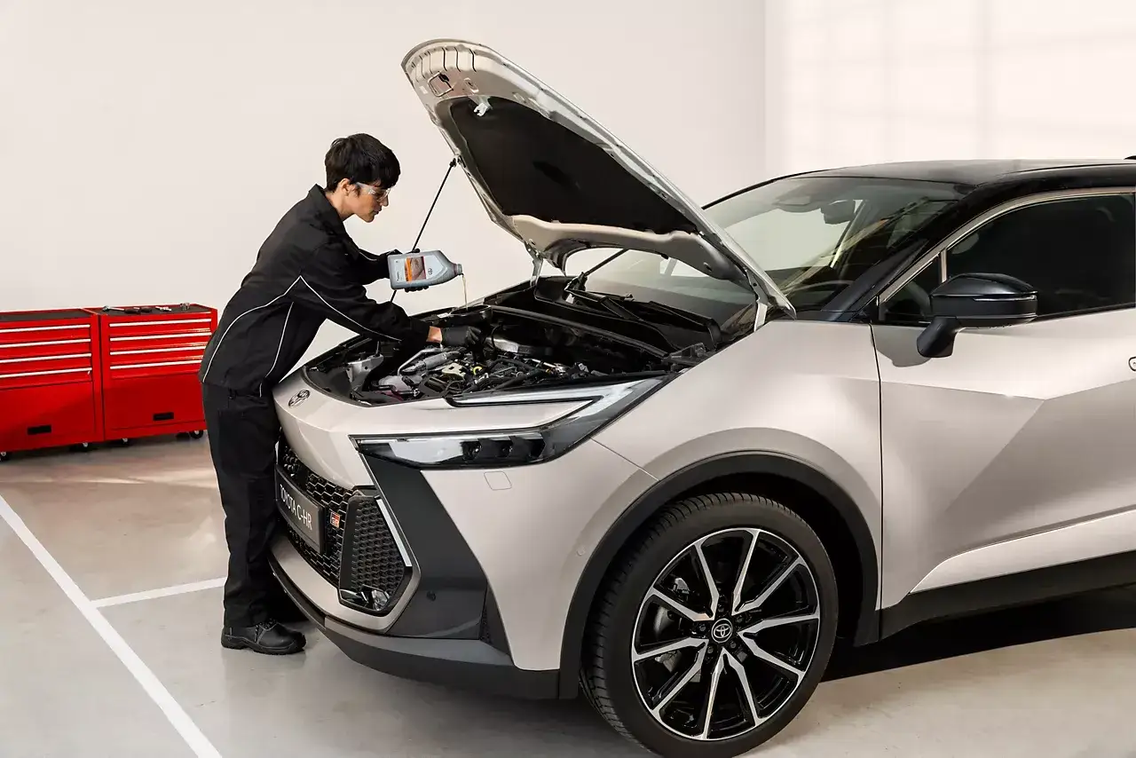 Mekaniker fyller på olja i en Toyota C-HR. För bästa service och pris på din Toyota Yaris, kontakta oss.
